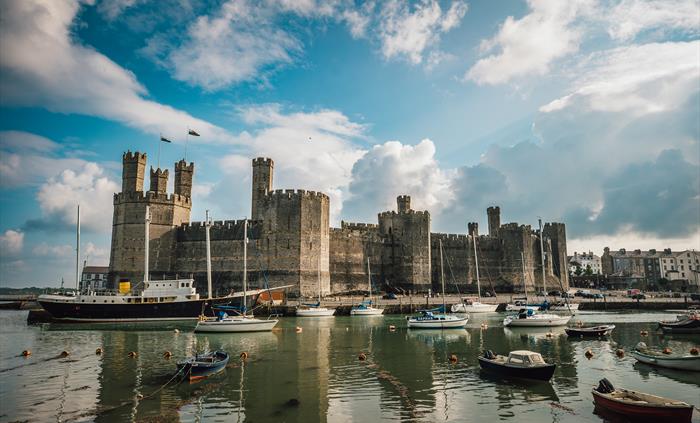 Castle with blue sky and white clouds and water in the foreground